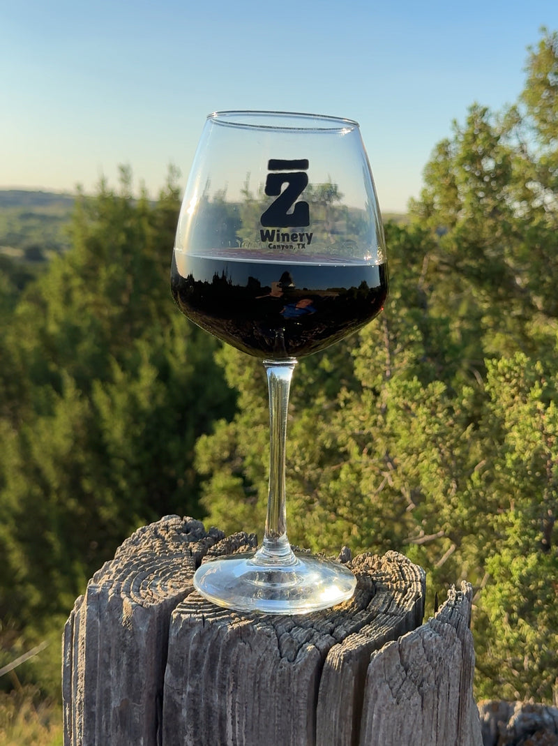 Wine glass with a logo on a wooden post against a natural background