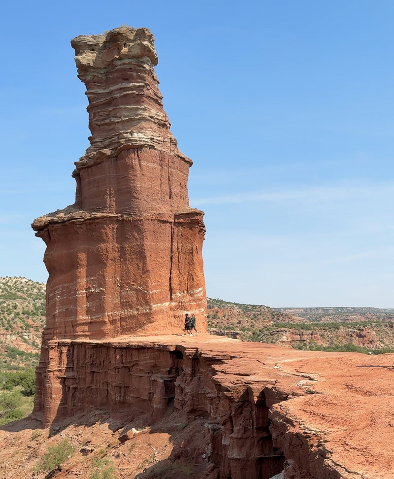 Palo Duro Canyon Lighthouse formation with a person for scale against a blue sky